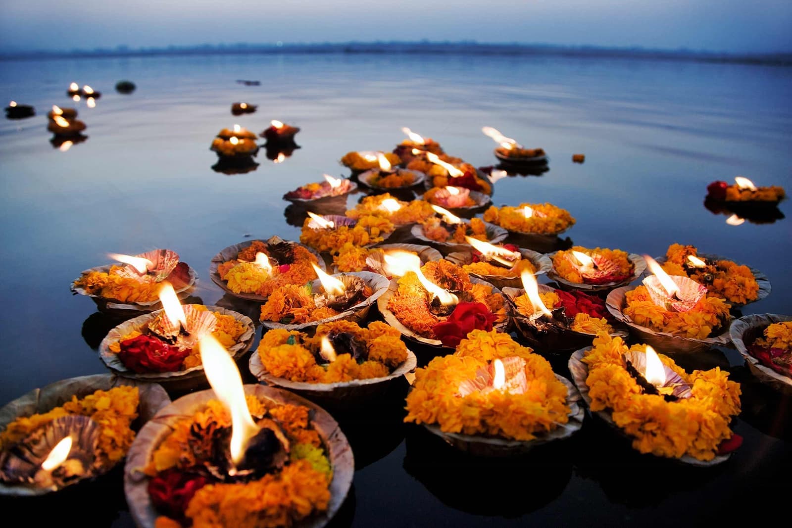 Devotional oil lamps on Ganges River during sunrise ceremony, Varanasi, India