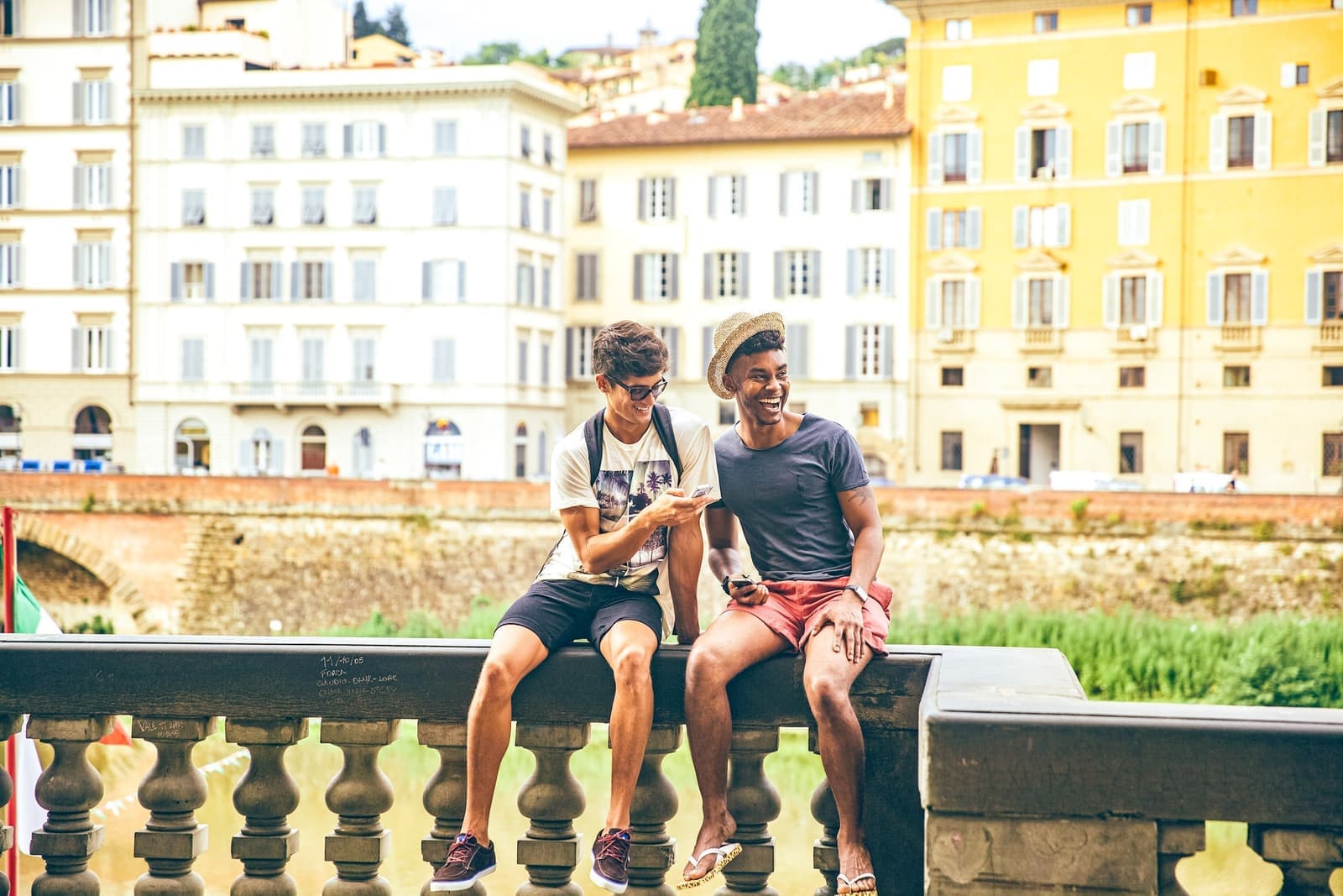 Travellers sitting on a wall on the River Arno in Florence, Italy