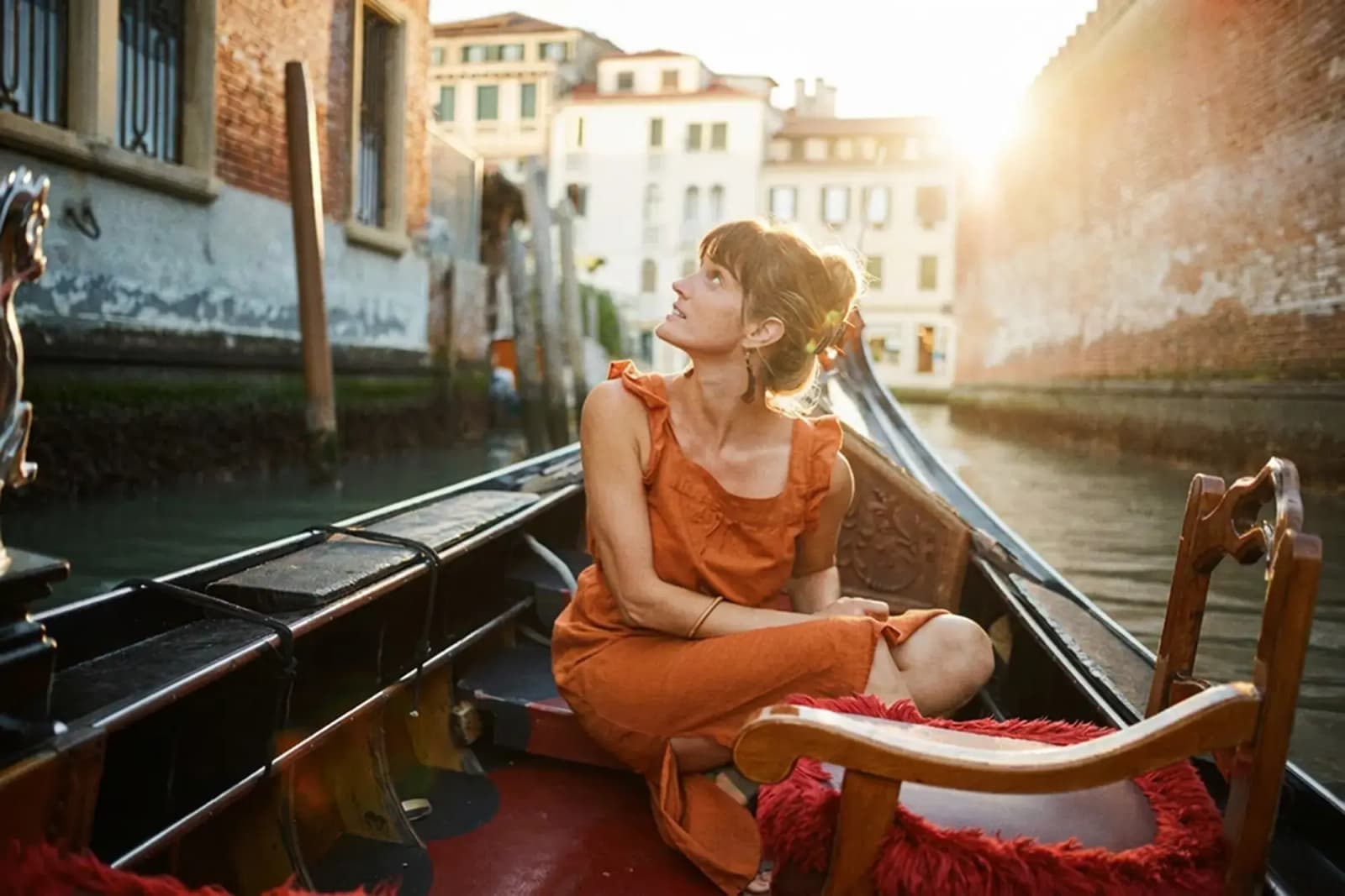 A woman looking upward while sitting on a gondola in Venice, Italy.