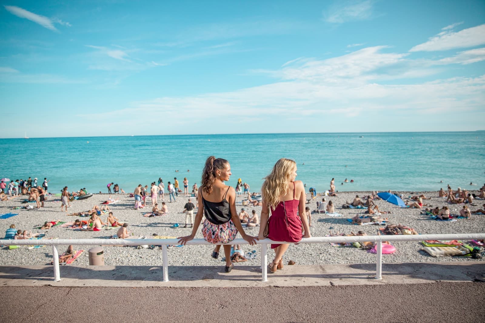 Travellers sitting on the promenade in front of the beachfront in the French Riviera, France