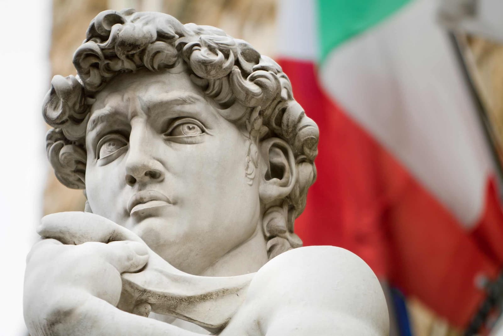 Close-up of Michelangelo’s David statue with Italian flag in background