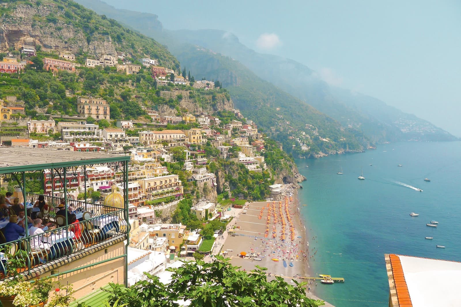 Positano beach with colourful umbrellas and hillside houses along Amalfi Coast