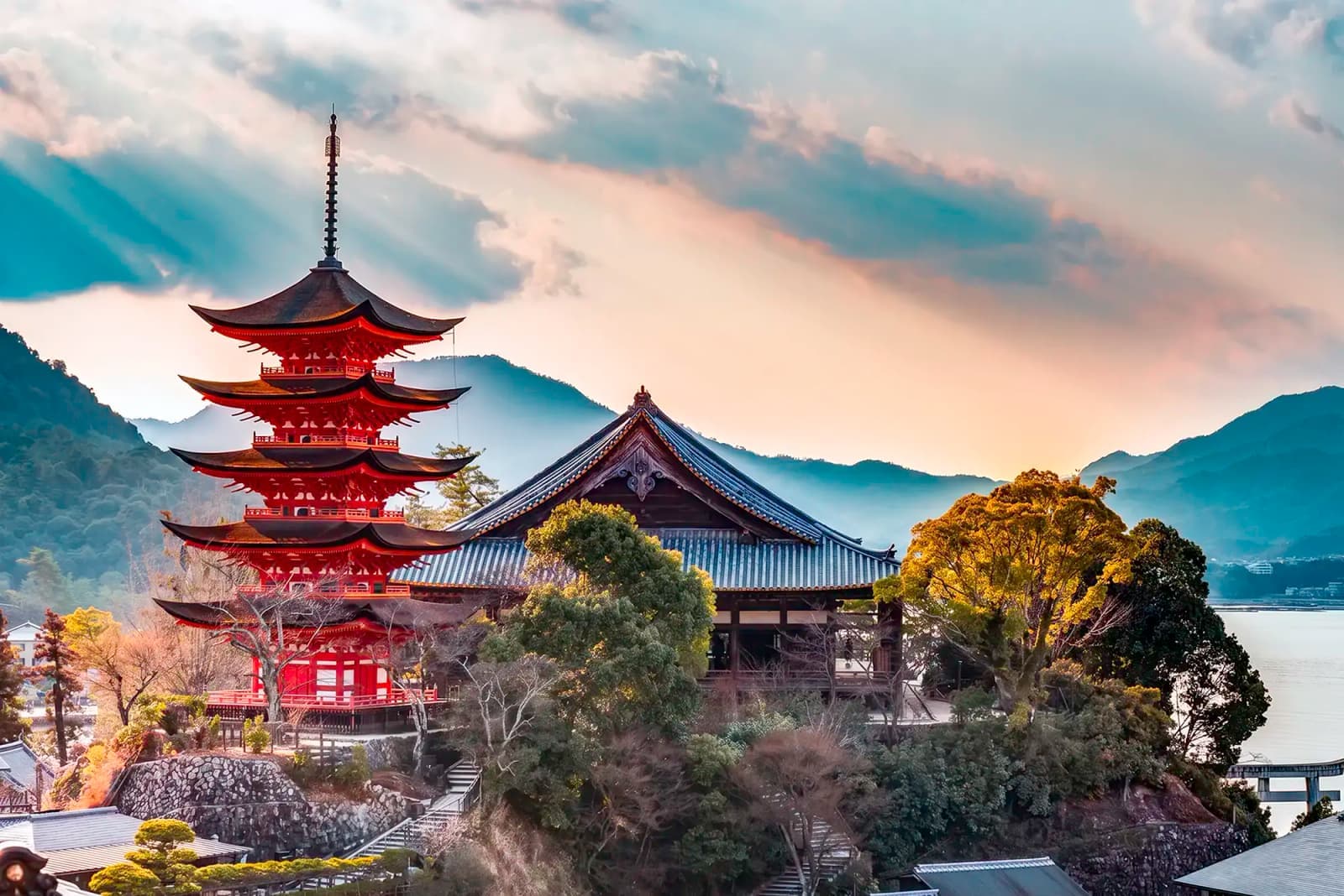 Five-story pagoda and temple buildings in Hiroshima, Japan, with mountains in the background.