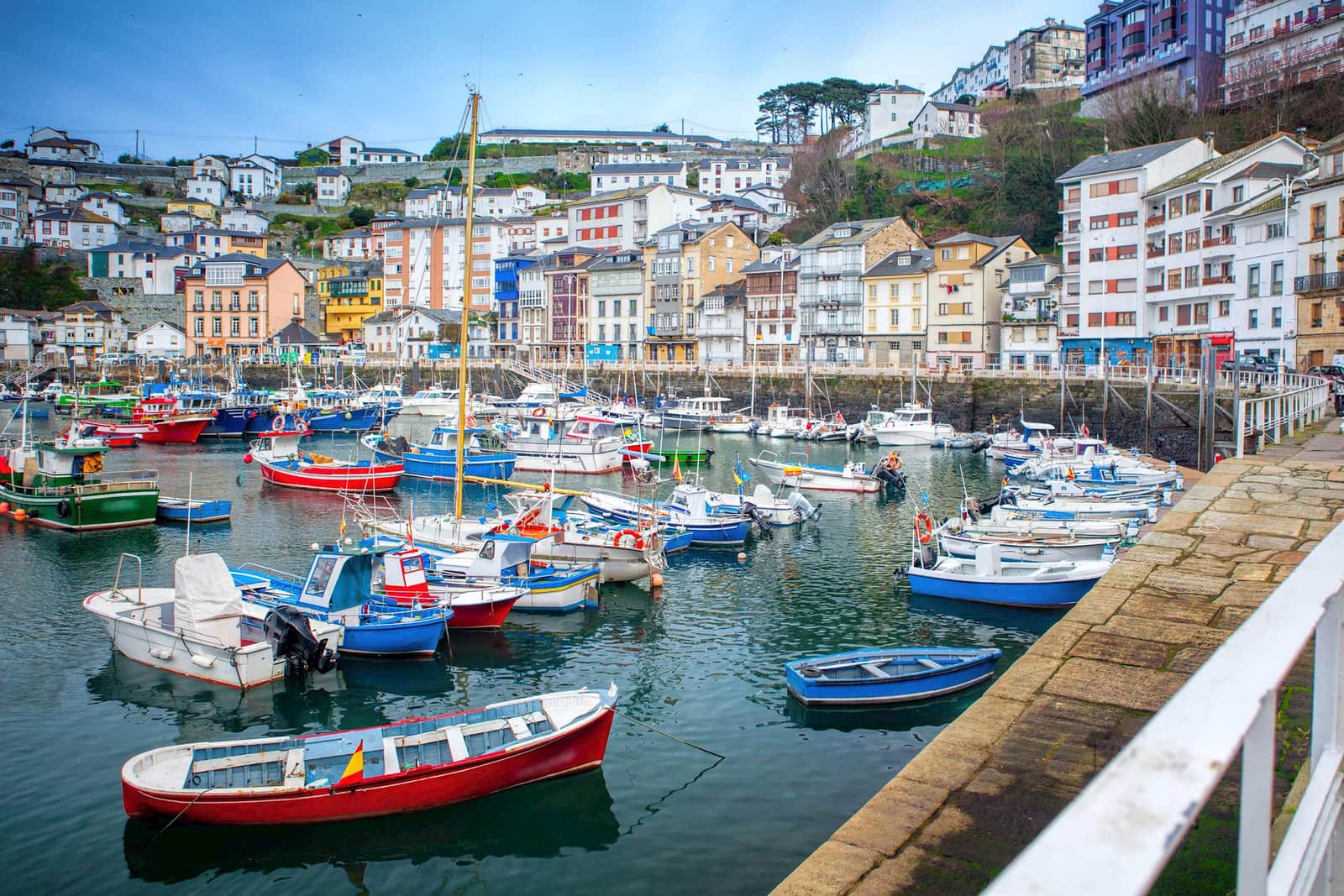 Colourful fishing boats in Luarca harbour with buildings