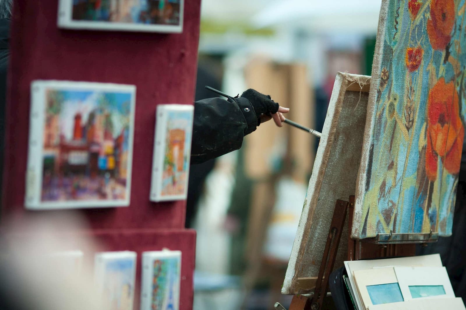 Outdoor artist painting outdoors with displayed canvases