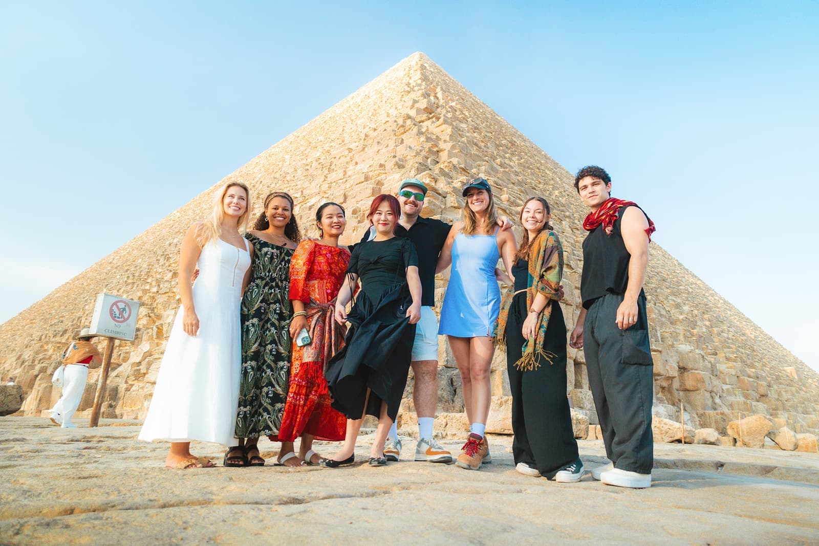 A group of travellers standing in front of a pyramid smiling at the camera in Cairo, Egypt