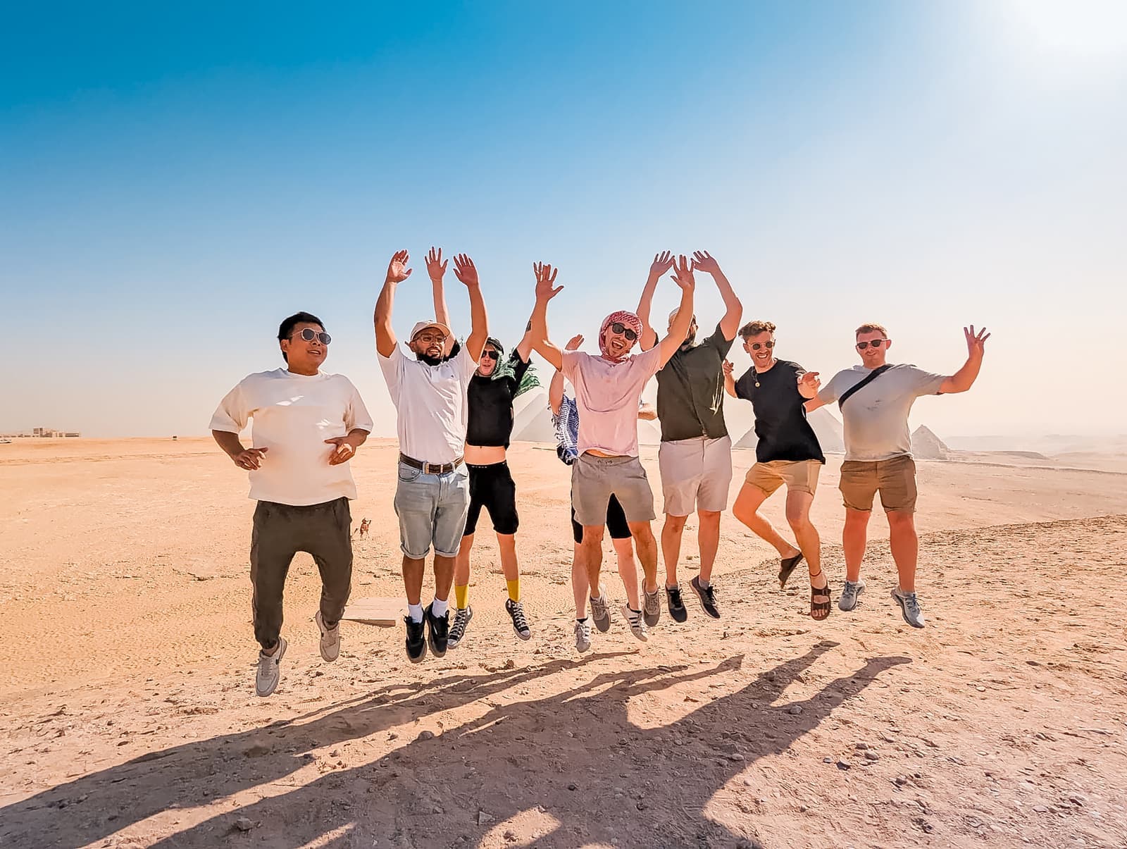 Group of travellers jumping up in the air in front of the pyramids in Cairo, Egypt