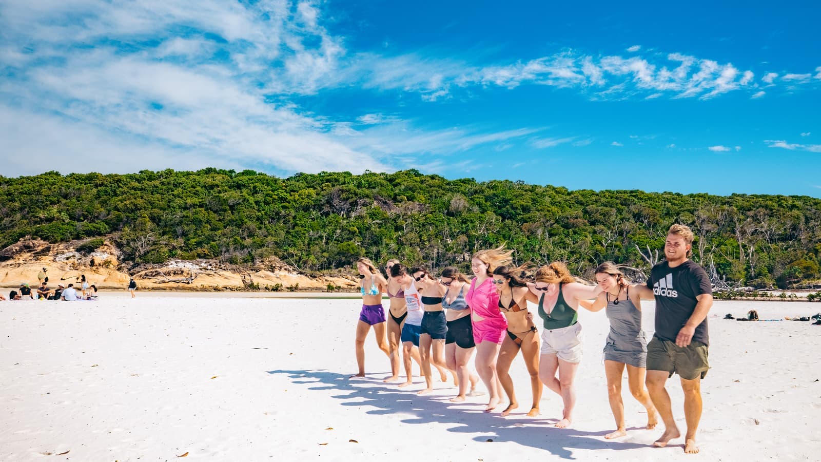Travellers walking across beach together, Whitsunday Islands, Australia