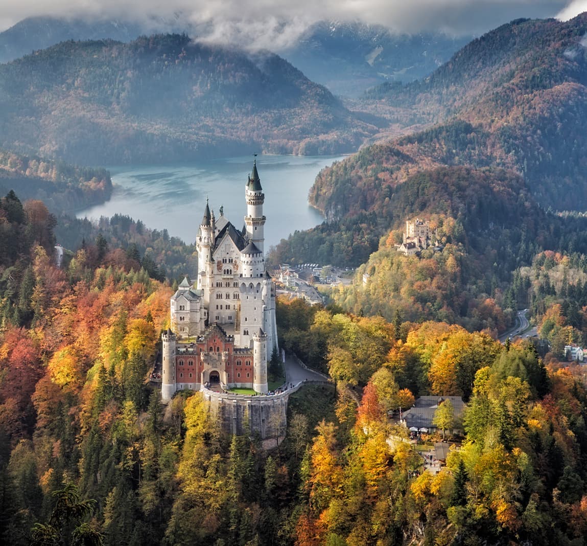 Neuschwanstein Castle surrounded by autumn forest and mountains