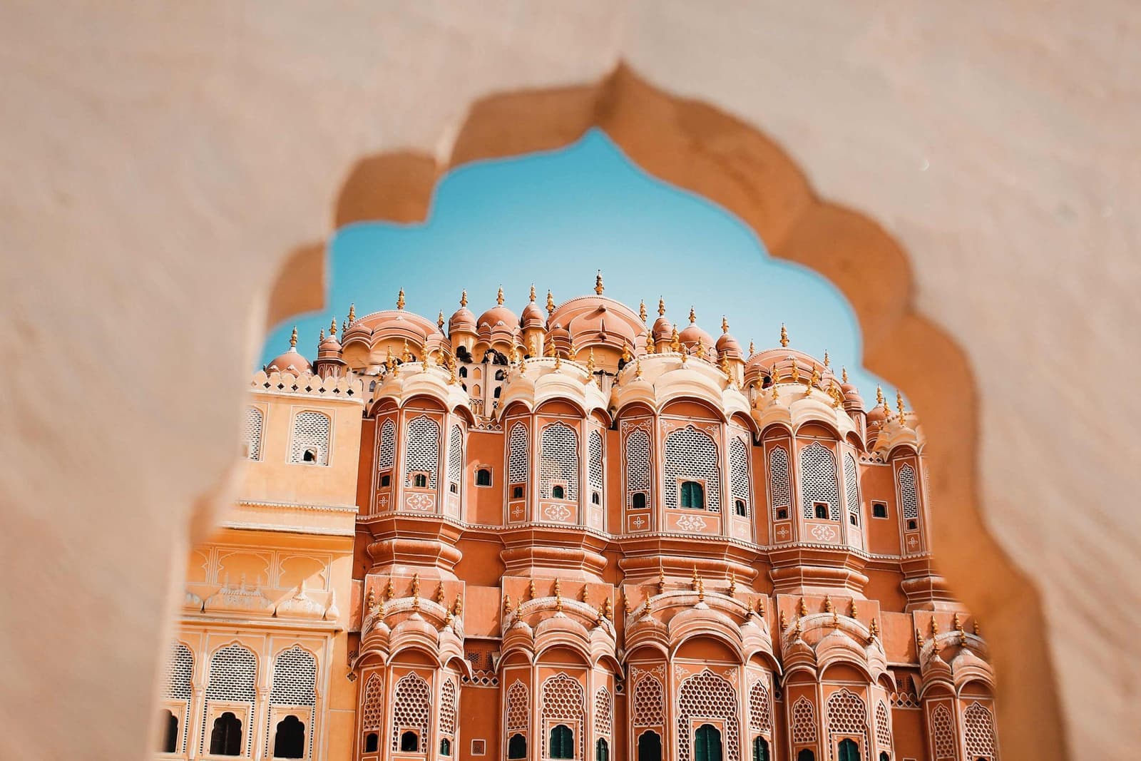 Arched window view overlooking pink sandstone palace of Hawa Mahal, Jaipur, India