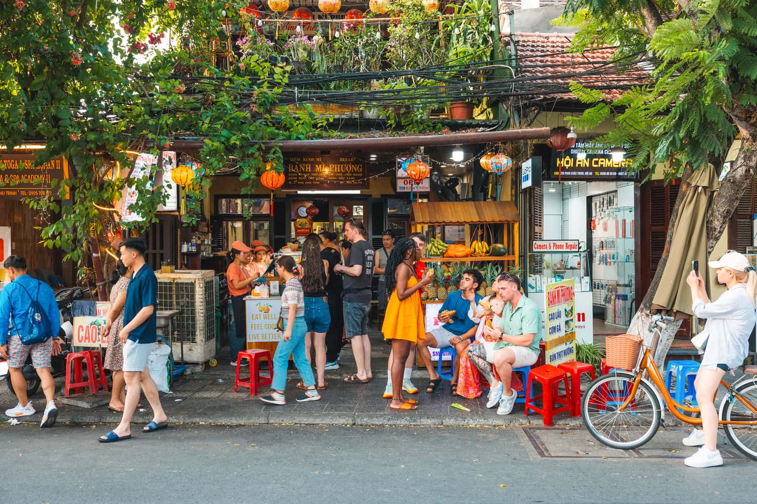 Travellers stood outside a food stall, decorated with lanterns, Hoi An, Vietnam