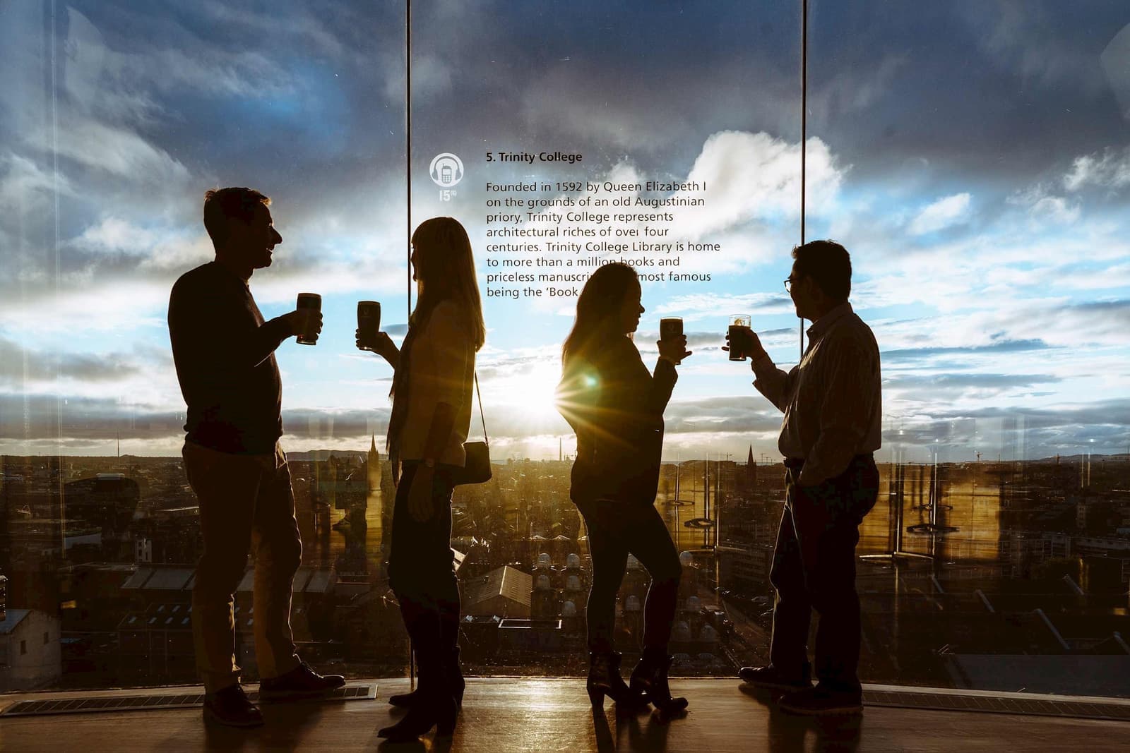 Visitors with Guinness pints at Gravity Bar overlooking Dublin cityscape