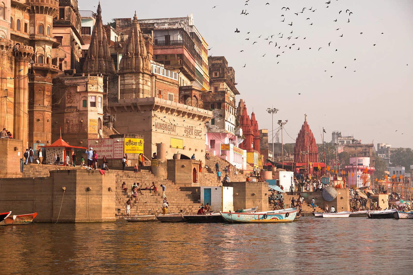 Historic stone buildings and colorful boats along India's Ganges River, Varanasi, India