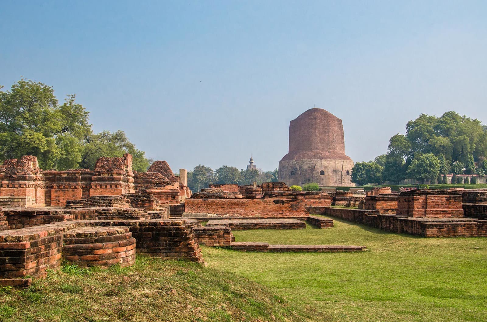 Ancient brick stupa tower behind sprawling low-walled ruins, Varanasi, India