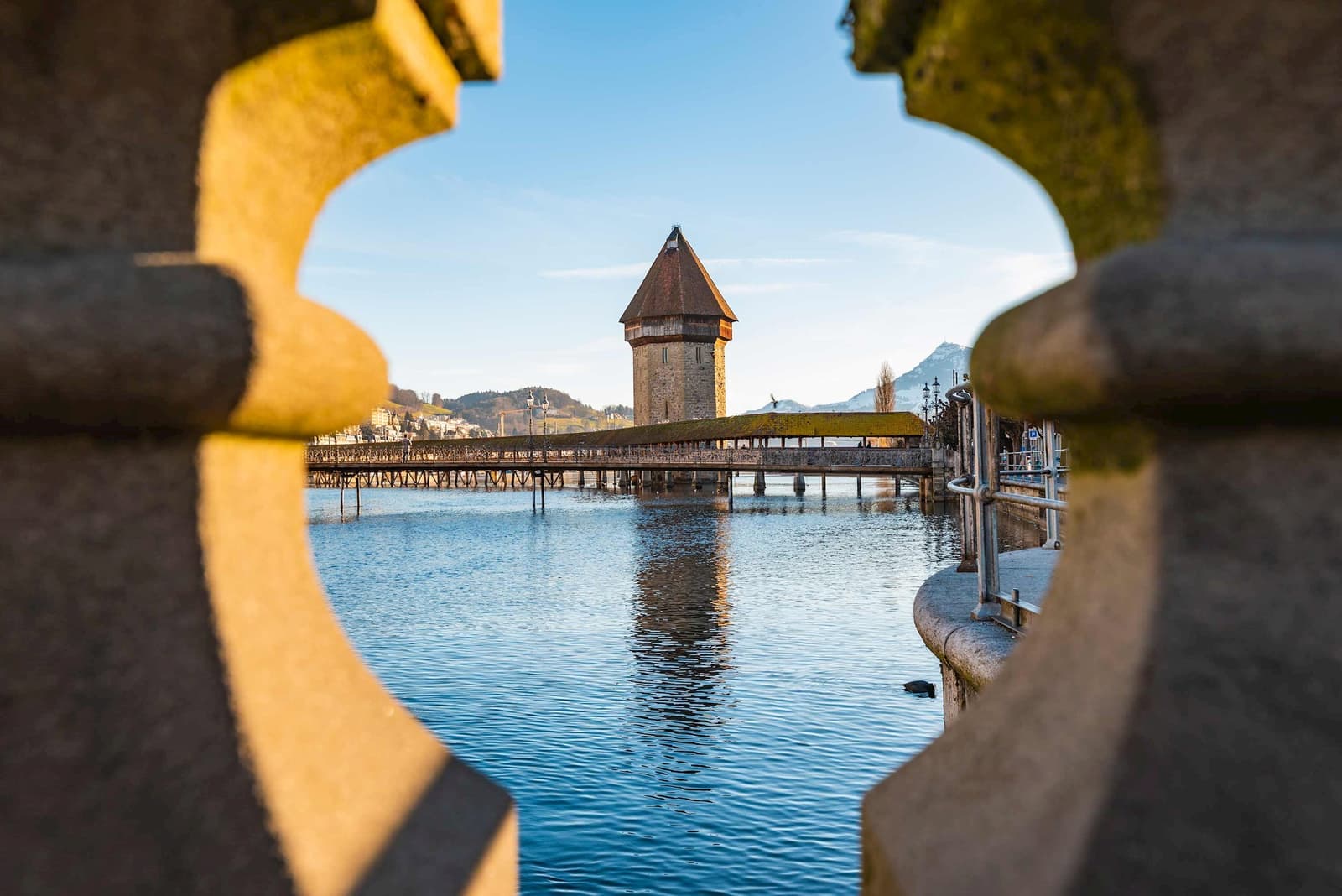Chapel Bridge and Water Tower over Reuss River, framed by stone balustrade in Lucerne, Switzerland
