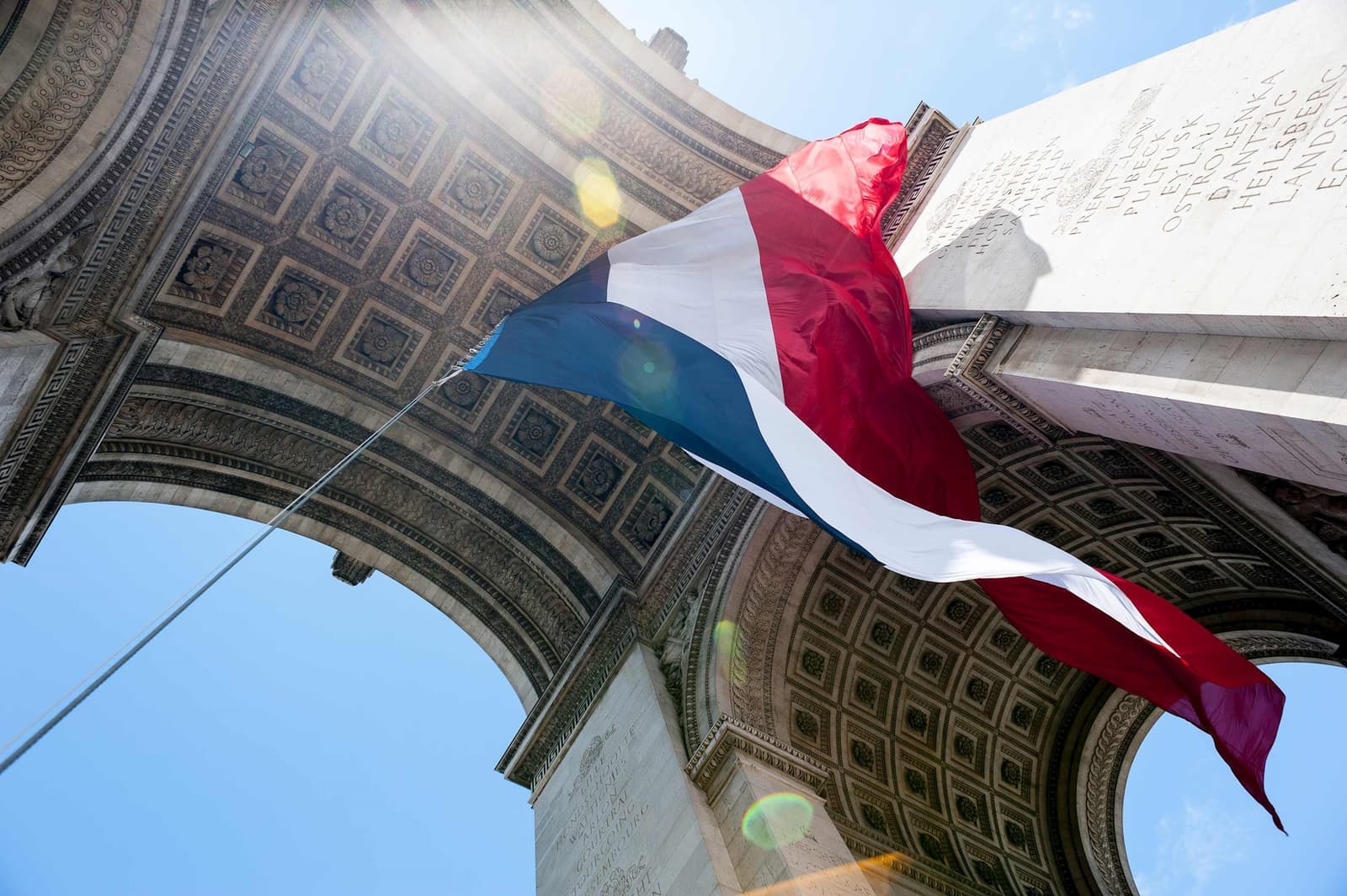 The French flag waving under the Arc de Triomphe