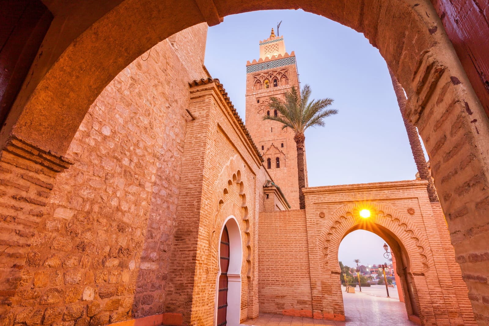 Koutoubia Mosque viewed through ornate stone arch at sunset in Marrakech, Morocco