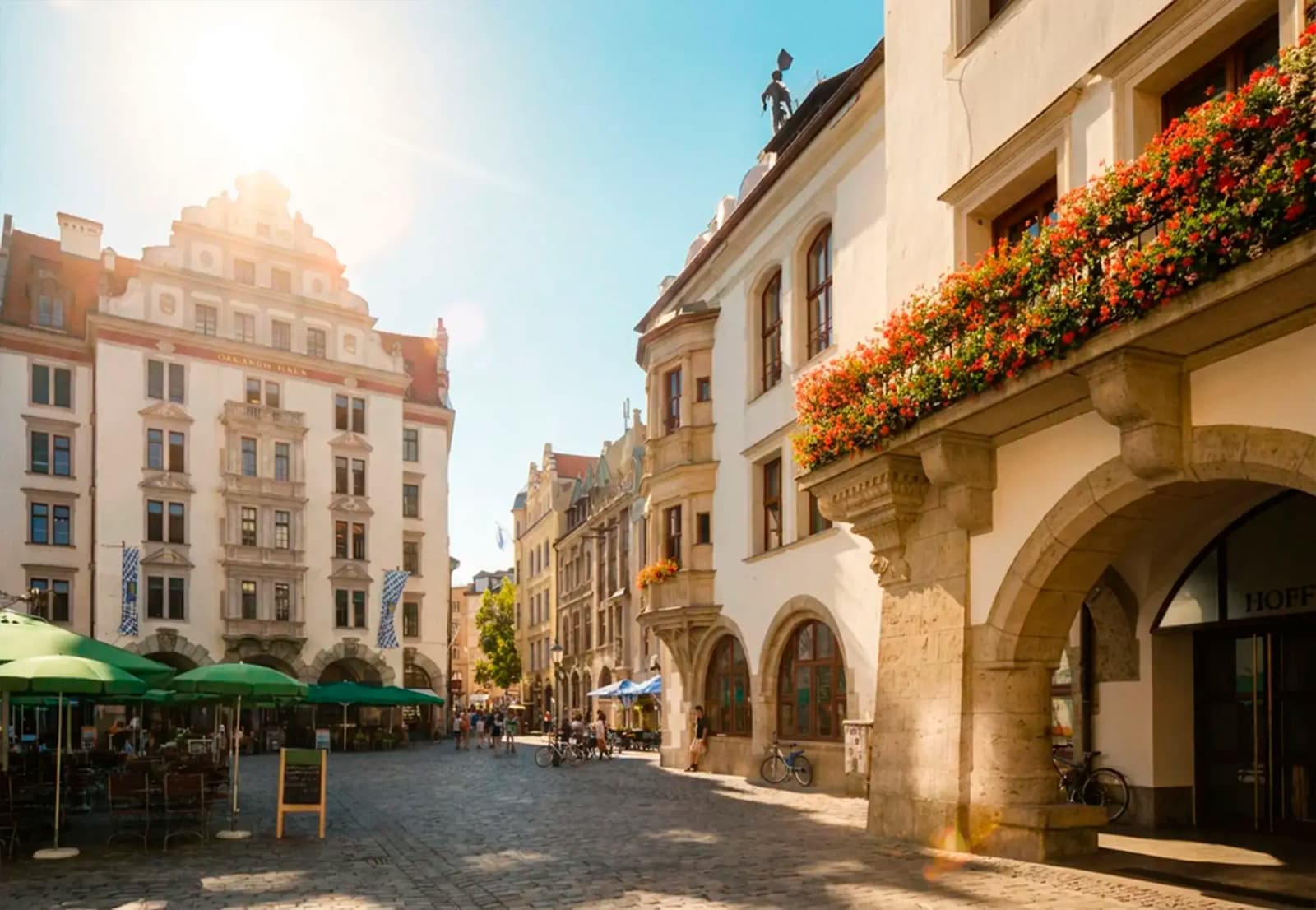 Buildings with flower-filled balconies along a cobblestone square in Munich, Germany.