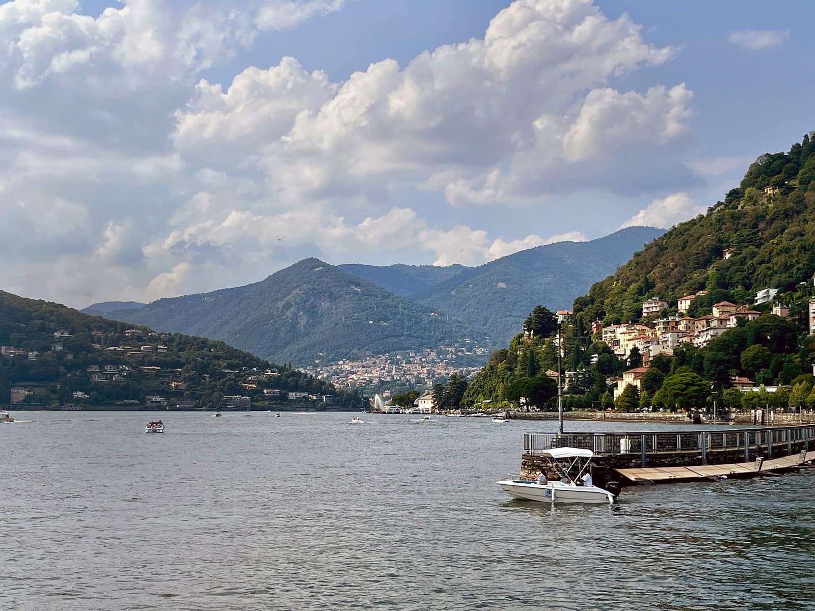 Scenic lakeside view with boats and houses under cloudy sky in Lake Como, Italy