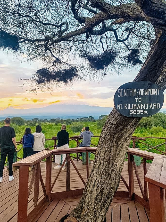 Travellers looking out at the sunset from a viewpoint in Amboseli, Kenya