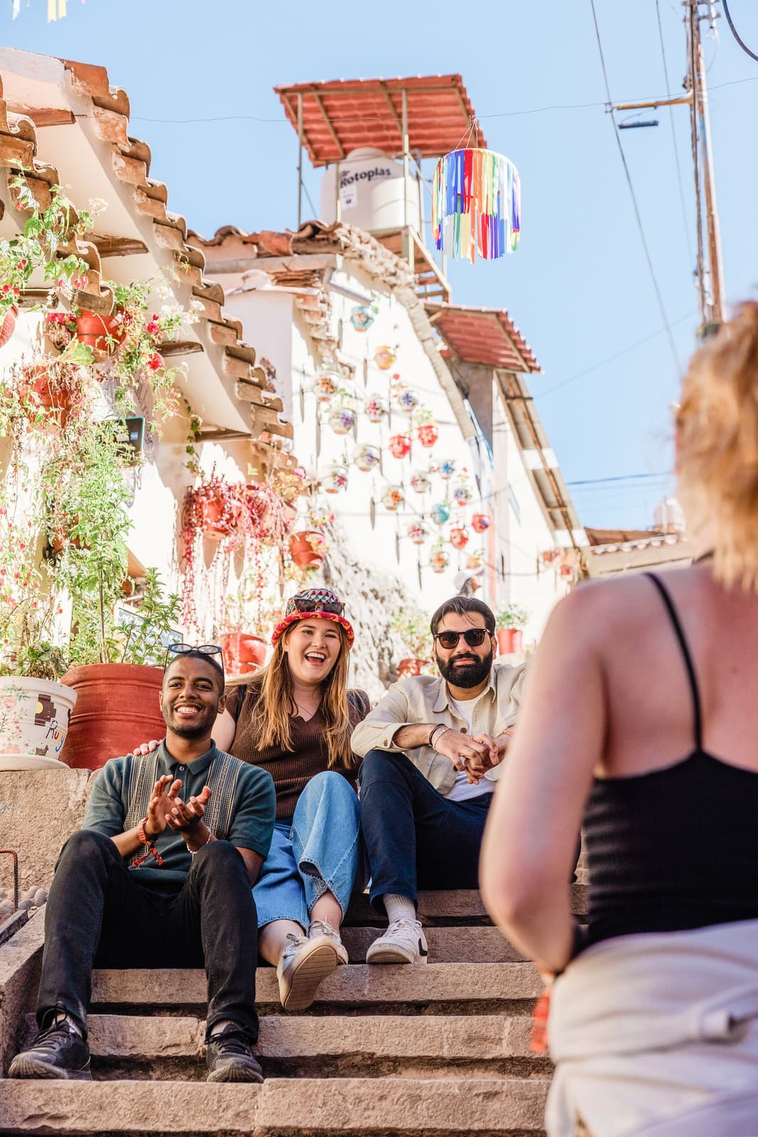 Three travellers sitting on steps surrounded by decorations and flowers in Cusco,Peru