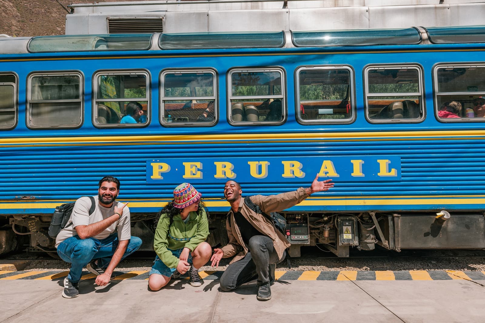 Three travellers posing next to a train in Sacred Valley, Peru