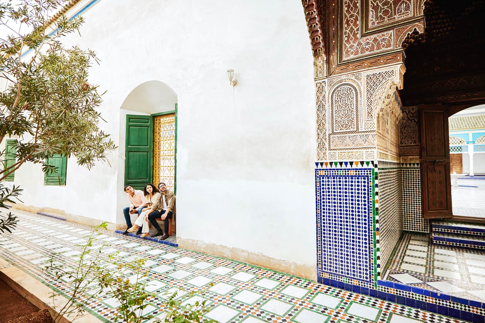 Travellers sitting on bench in the courtyard of the Bahia palace in Marrakesh, Morocco