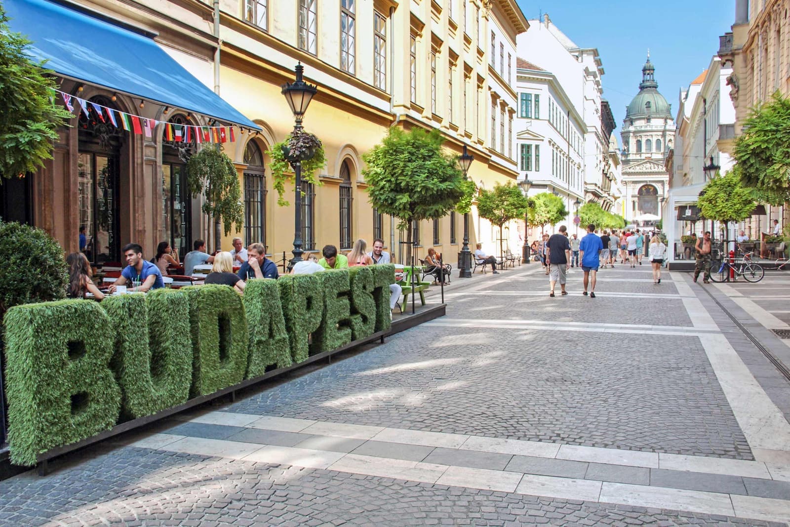 A street view of a bush shaped to spell "Budapest"