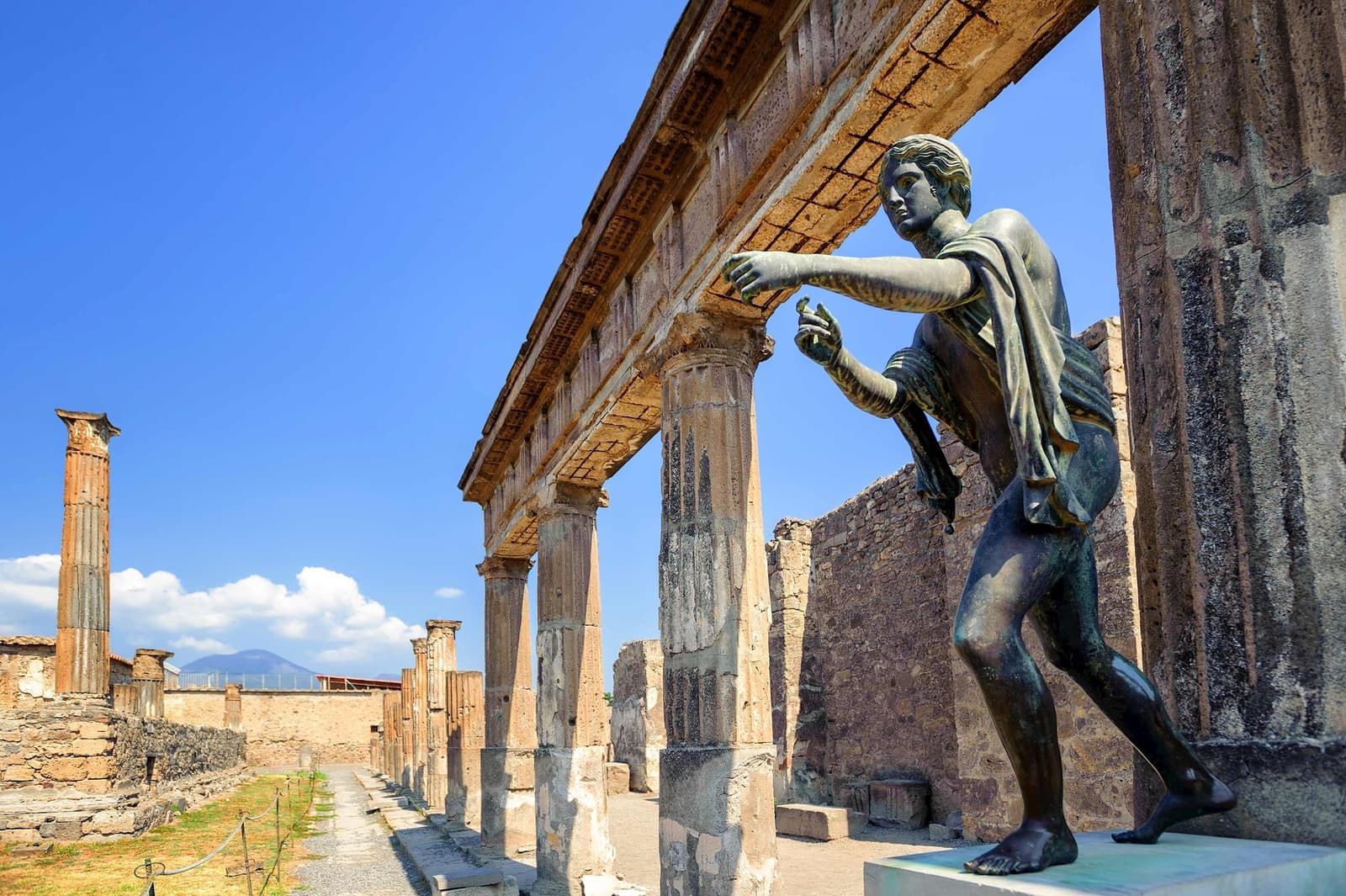 Bronze statue at Temple of Apollo in Pompeii with ancient stone columns and ruins