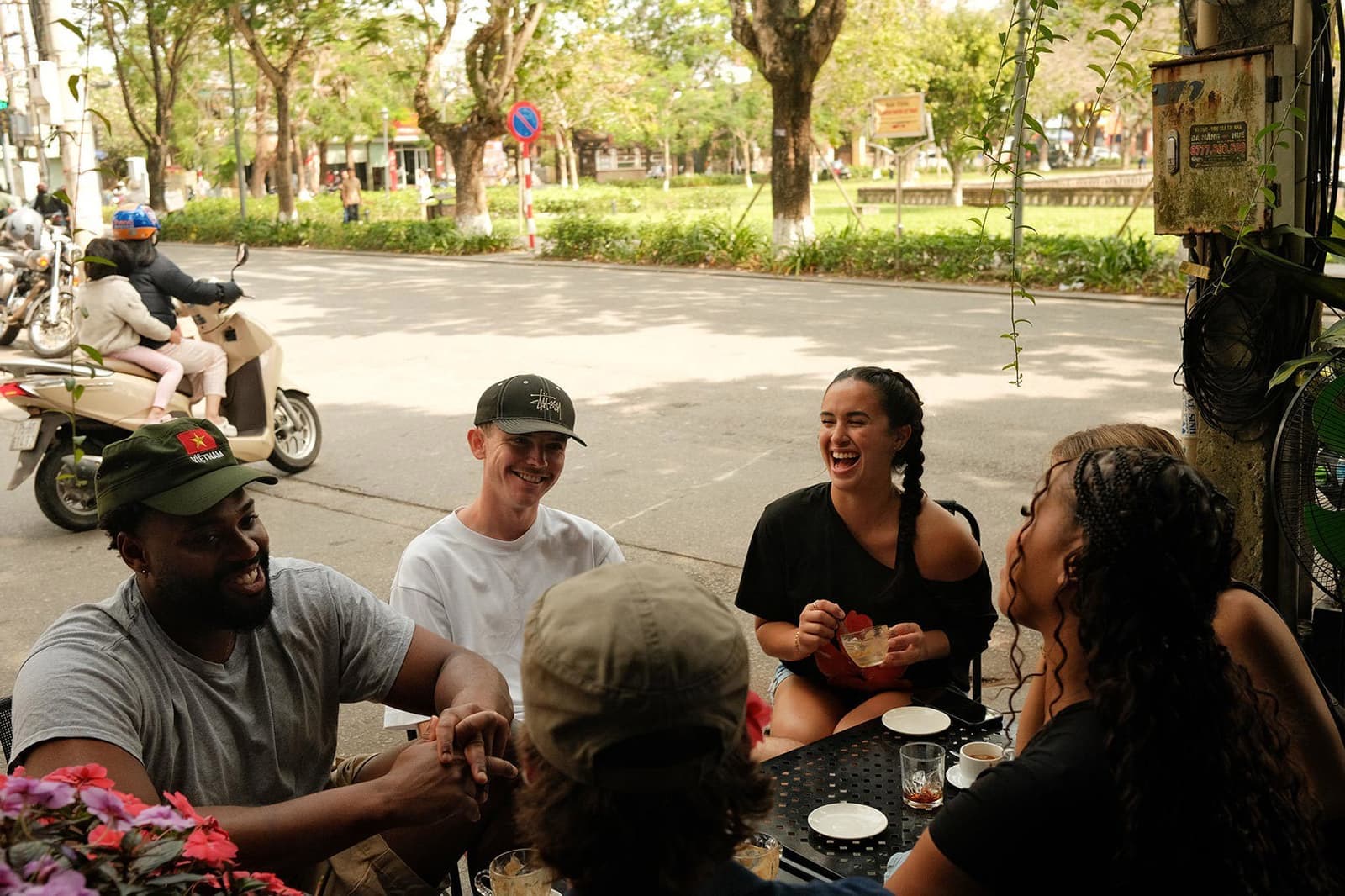 Travellers laughing at a busy outdoor cafe, Hue, Vietnam.