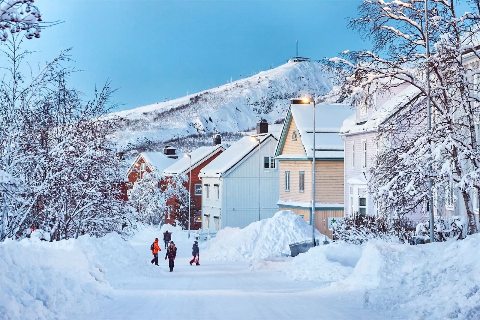 Snow-covered street with colourful houses and mountain backdrop in Kiruna, Sweden