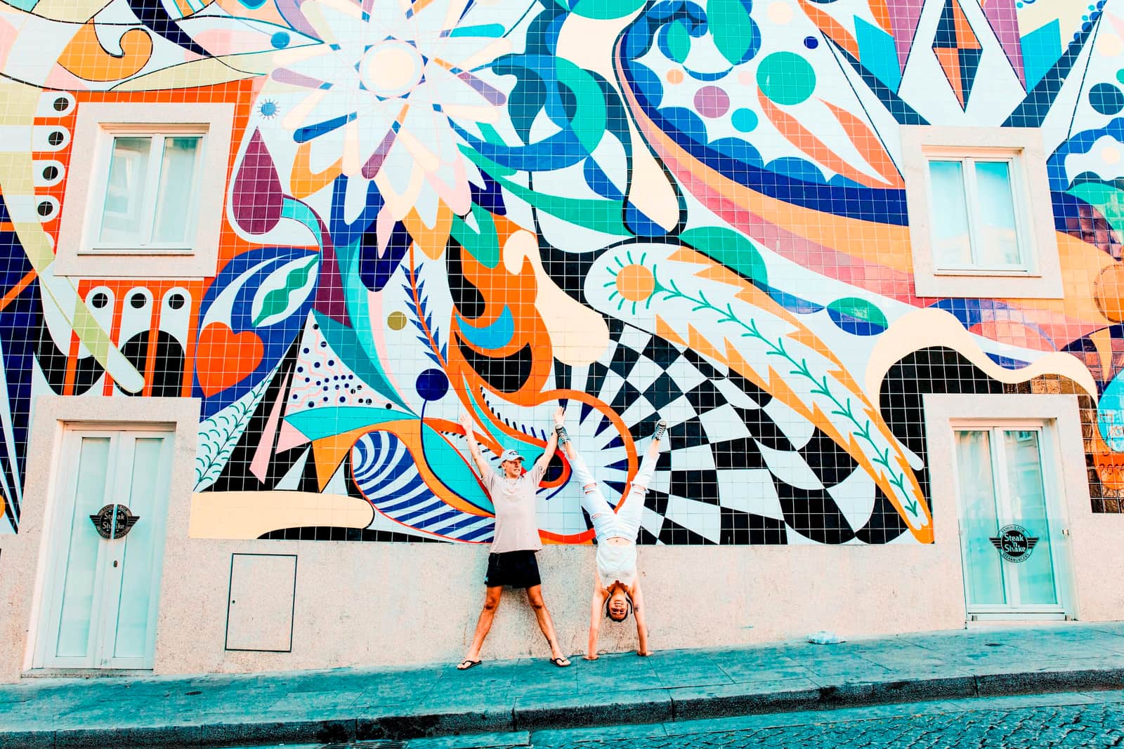 Travellers posing in front of a colourful mosaic in Porto, Portugal
