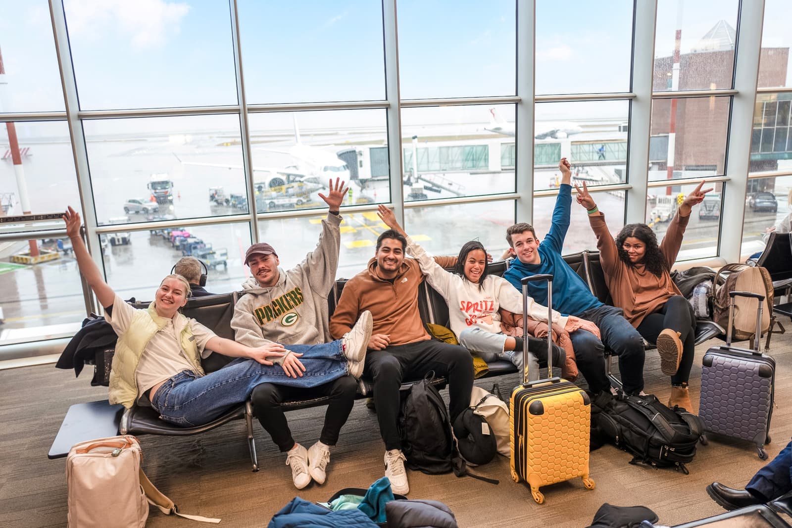 Six travellers sitting in the airport, posing for a picture, Alice Springs, Australia