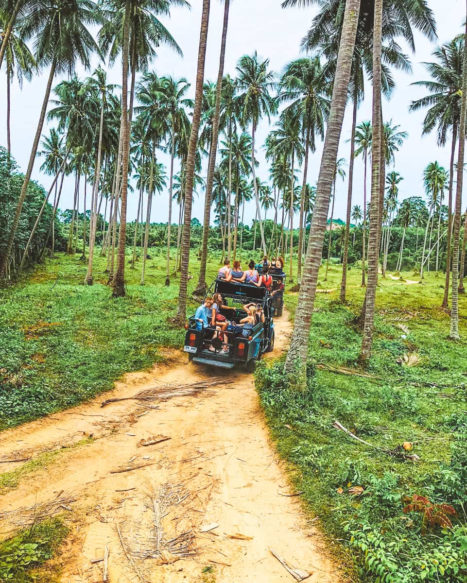 Travellers on a dirt road driving in a Jeep vehicle on a safari in Koh Samui, Thailand