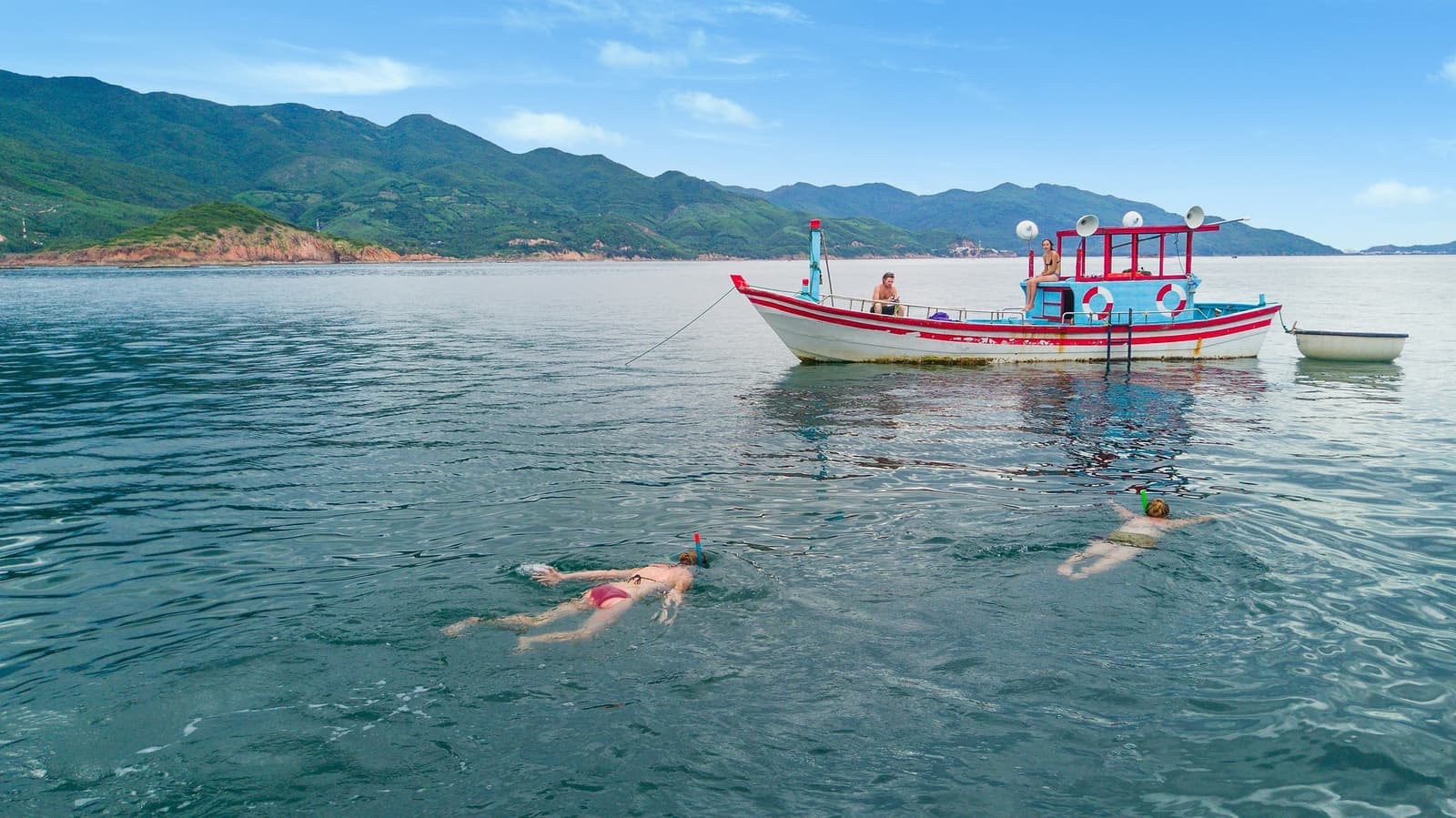 People swimming beside a wooden boat in Hoi An, Vietnam