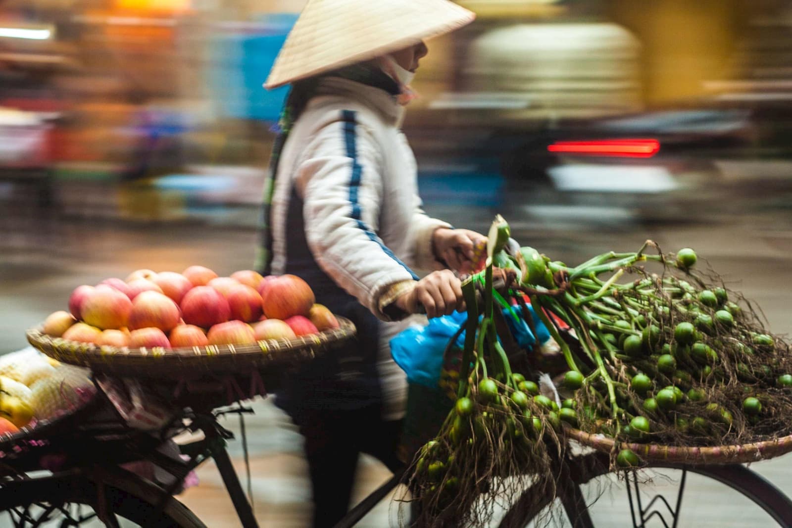 Fruit vendor cycling with baskets full of produce in Ho Chi Min, Vietnam