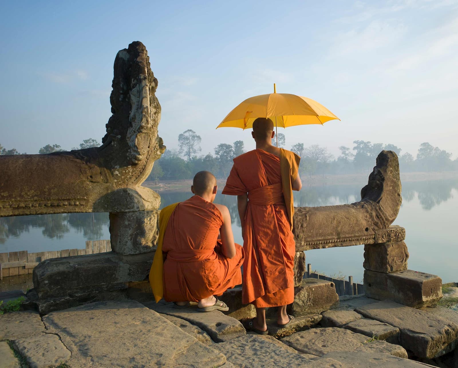 Two Buddhist monks standing by water at Angkor Wat, Cambodia