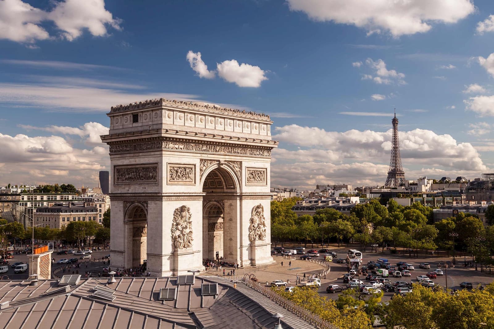 Arc de Triomphe with Eiffel Tower in background and busy roundabout in Paris, France