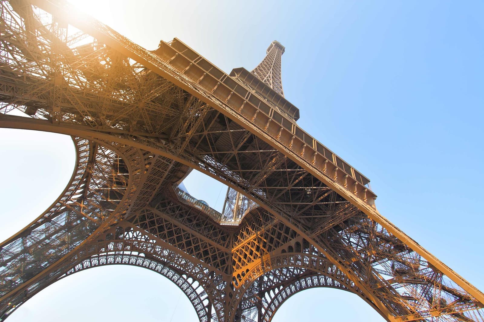 Eiffel Tower iron lattice viewed from below against blue sky in Paris, France